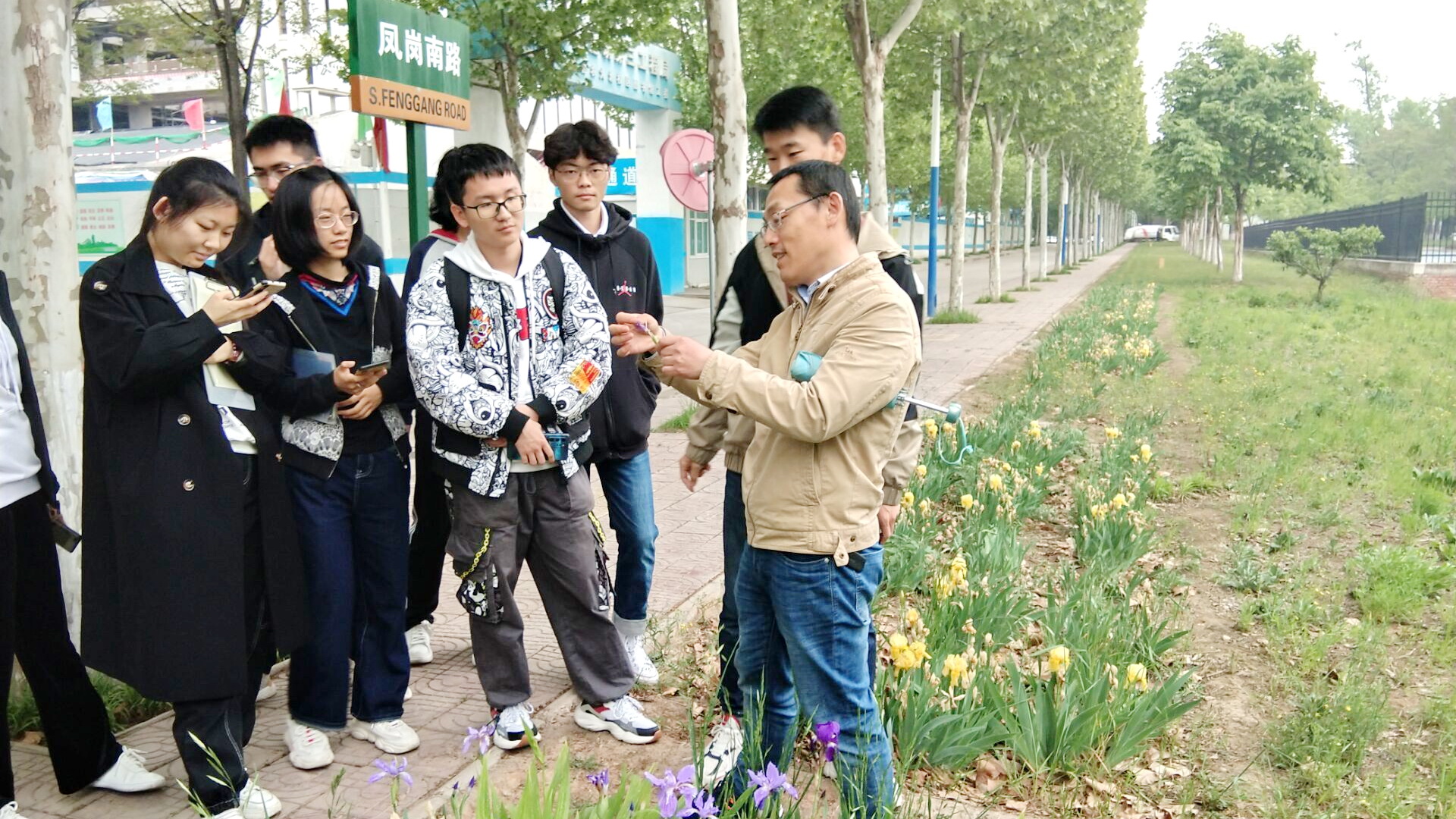 李刚老师在校园里带领同学们认识植物